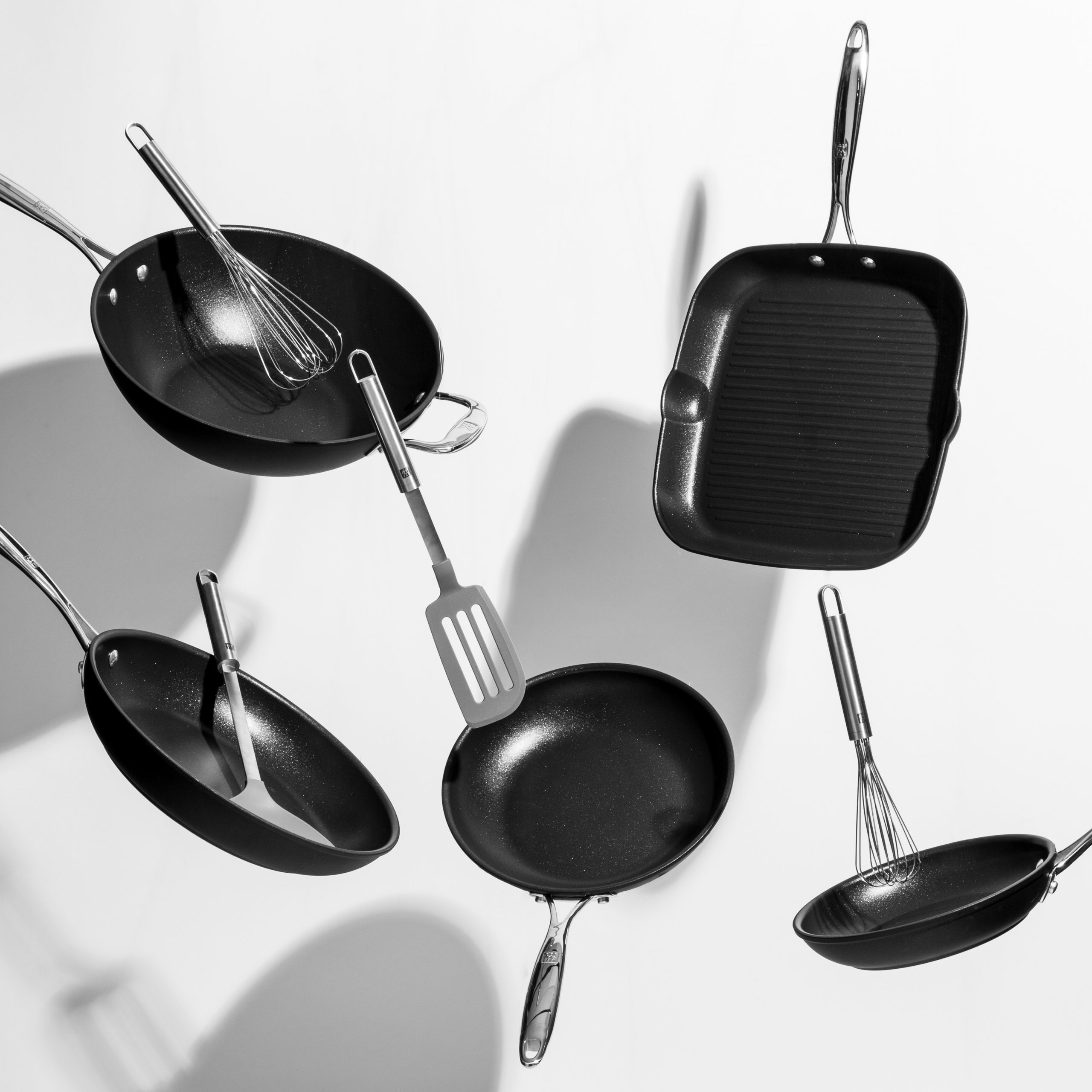 Interesting shot of trendy black kitchen utensils dancing on white background